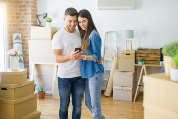 Young couple moving to a new house, using smartphone smiling very happy for new apartment