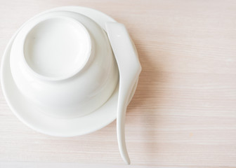 In the picture, the dishes, bowls, cups, spoons are placed neat and clean on the wooden table.
