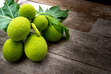 Breadfruit with green leaf  isolated on old wooden background. 