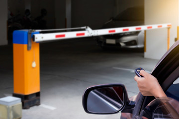 Woman in car, hand using remote control to open the automatic barrier of the car parking .Home...