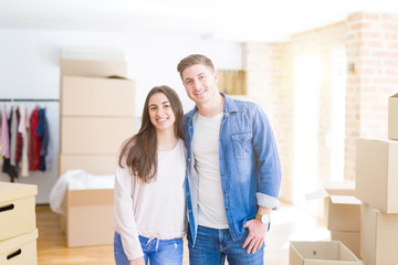 Fototapeta na wymiar Beautiful young couple moving to a new home, standing on new aparment around cardboard boxes, hugging smiling happy and in love