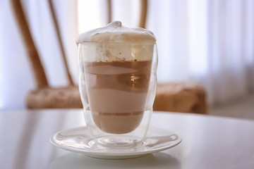 Glass of tasty frappe coffee on table in cafe