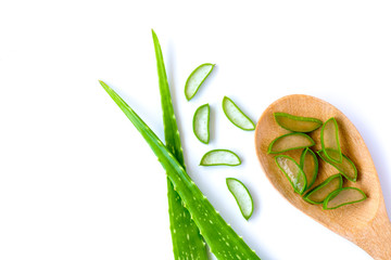 Green fresh aloe vera leaves and slices in wooden spoon isolated on white background.Top view.