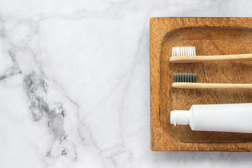 Set of eco-friendly toothbrushes and toothpaste on wooden stand and marble background. Dental and healthcare concept. Top view, flat lay. Free copy space.