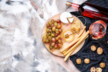 Glass and bottle of tasty wine with snacks on color background