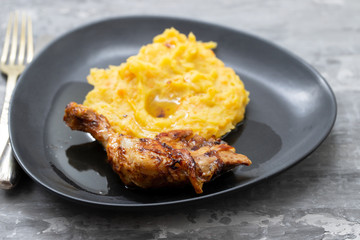 chicken with mashed sweet potato on black dish
