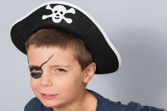 Boy in a pirate costume on gray background