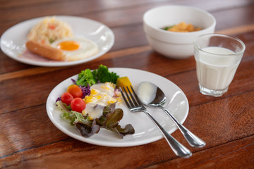 vegetable salads, sausages, fried rice, milk and orange juice on a brown wooden table