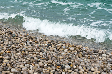 Fototapeta na wymiar waves crash onto a rock and pebble beach