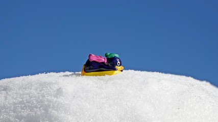 a toy penguin with a yellow slide on snow