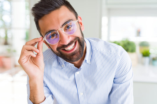 Handsome business man wearing glasses and smiling cheerful with confident smile on face