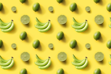 Seamless tropical pattern bananas, limes on yellow background. Creative food concept. Flat lay. Top view.