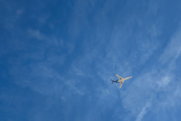 the plane flies against the blue sky