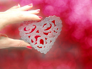 heart in woman's hand on abstract blurred background