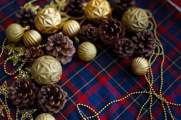 Frame of christmas decorations cones and golden balls on the blue-red plaid background. New Year Flat lays concept. 