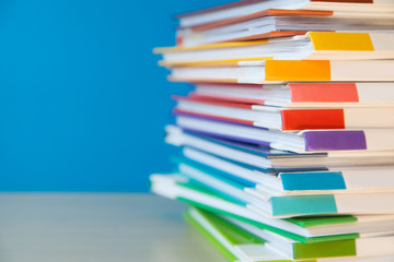 Stack of colorful books on color background.