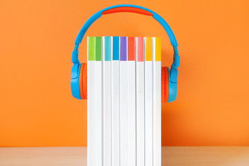 Colorful Headphones and books on color background. Concept of audiobook.