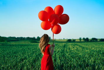 Back view of freedom happy woman running with red balloons on green summer field - Powered by Adobe