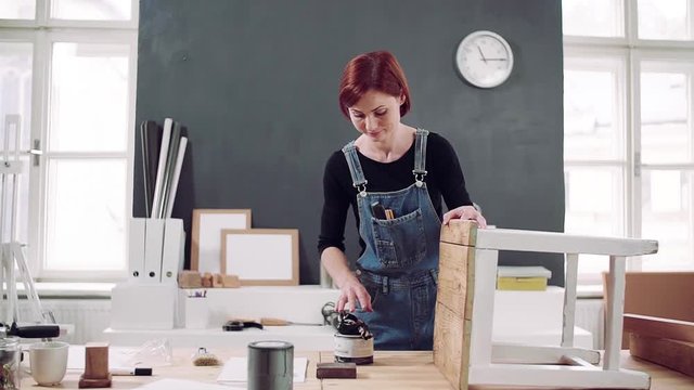 Young woman indoors restoring old furniture. Slow motion.