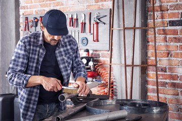 Metalworker cleaning off a metal pipe with a brush