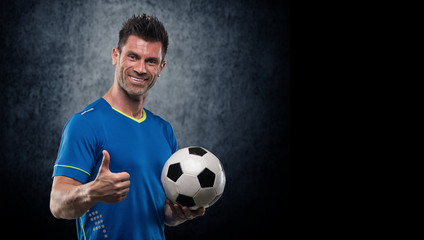 Happy soccer player holding ball isolated on a white background. Looking at camera © romanolebedev