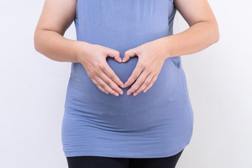 Pregnant woman in blue dress holds belly on a white background. close up of happy pregnancy hands touch on tummy healthy concept. motherhood stand wait for childbirth in hospital.
