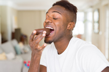 African american man eating  and enjoying a sweet chocolate donut