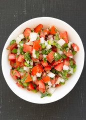 Fototapeta na wymiar Pico de Gallo in a white bowl on a black surface. Overhead, from above, flat lay.