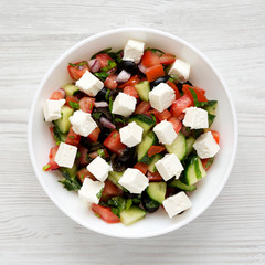 Homemade Shepards salad with cucumbers, feta and parsley in a white bowl, top view. From above, overhead, flat lay. Close-up.