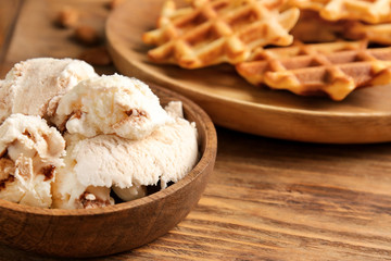 Bowl with tasty ice-cream and waffles on table, closeup