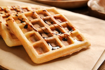 Tasty waffles with chocolate on table, closeup