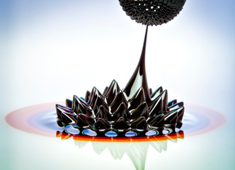 Ferrofluid flow. Macro photograph of Ferrofluid flowing from one magnet to another. Colloidal...