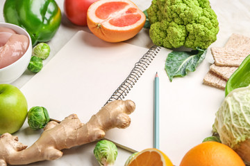 Notebook with healthy products on white table. Diet concept