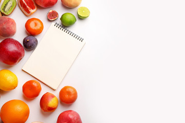 Naklejka na ściany i meble Notebook with fresh fruits on white background. Diet concept