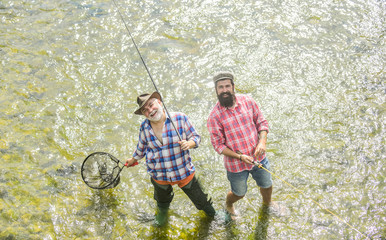 Collaboration. two happy fisherman with fishing rod and net. father and son fishing. Poaching. Camping on the shore of lake. Big game fishing. friendship. concept of rural getaway. hobby. wild nature