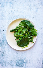 Fresh green spinach leaves on plate.