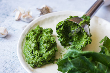 Green fresh pesto dip paste with spinach and nuts. Made with blender on plate. Vegan or vegetarian food.