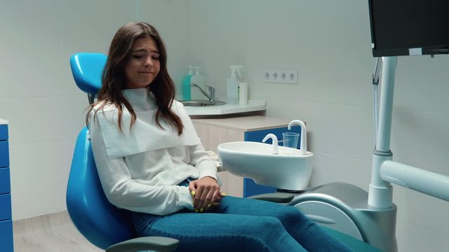 brunette woman patient looks nervous while sitting in the dentist's office feels frightened