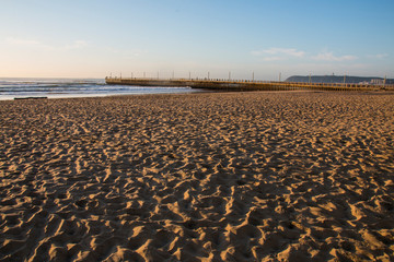 Beach Covered in Human Footprints with Pier and Bluff