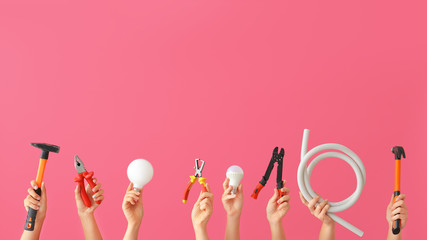 Female hands with electrician's tools on color background