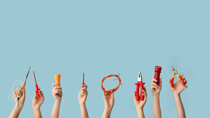 Female hands with electrician's tools on color background