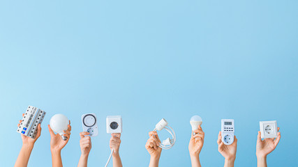 Female hands with electrician's tools on color background