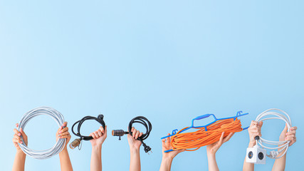 Female hands with electrician's tools on color background
