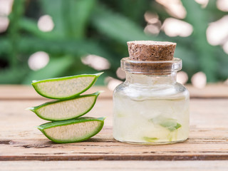 Fresh aloe leaves and aloe gel in the cosmetic jar on wooden table.
