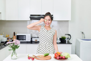 Healthy food at home. Happy woman is preparing the vegetables and fruit in the kitchen.