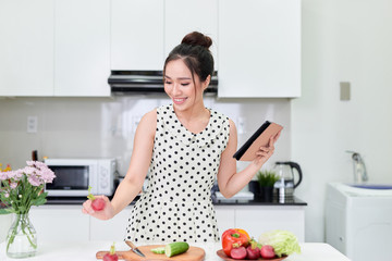 woman using tablet while making a healthy salad at the kitchen