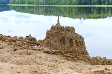 Sand building on the beach. Sand castle on the shore of the pond.