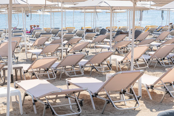 Sunbeds and parasols on morning, by the sea water. Beach in luxury resort near sea. Beautiful morning seascape. Tourist places. Typical mediterranean beach, a place holidays in summer, Greece