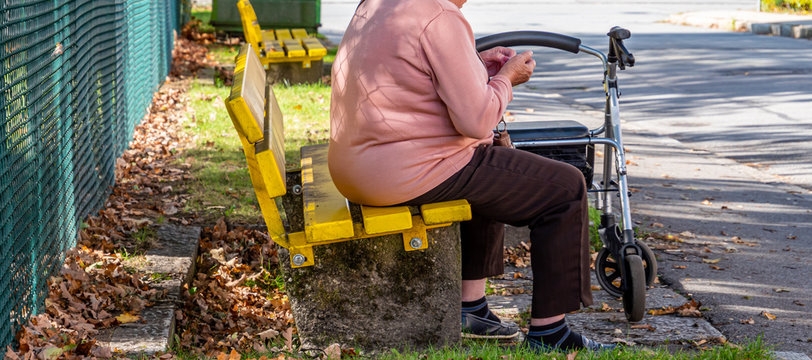 Alte Frau sitzt auf einer Bank