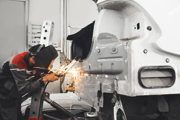 Man wearing protective mask while repairing rear car body with welding machine. Weld of vehicle.
